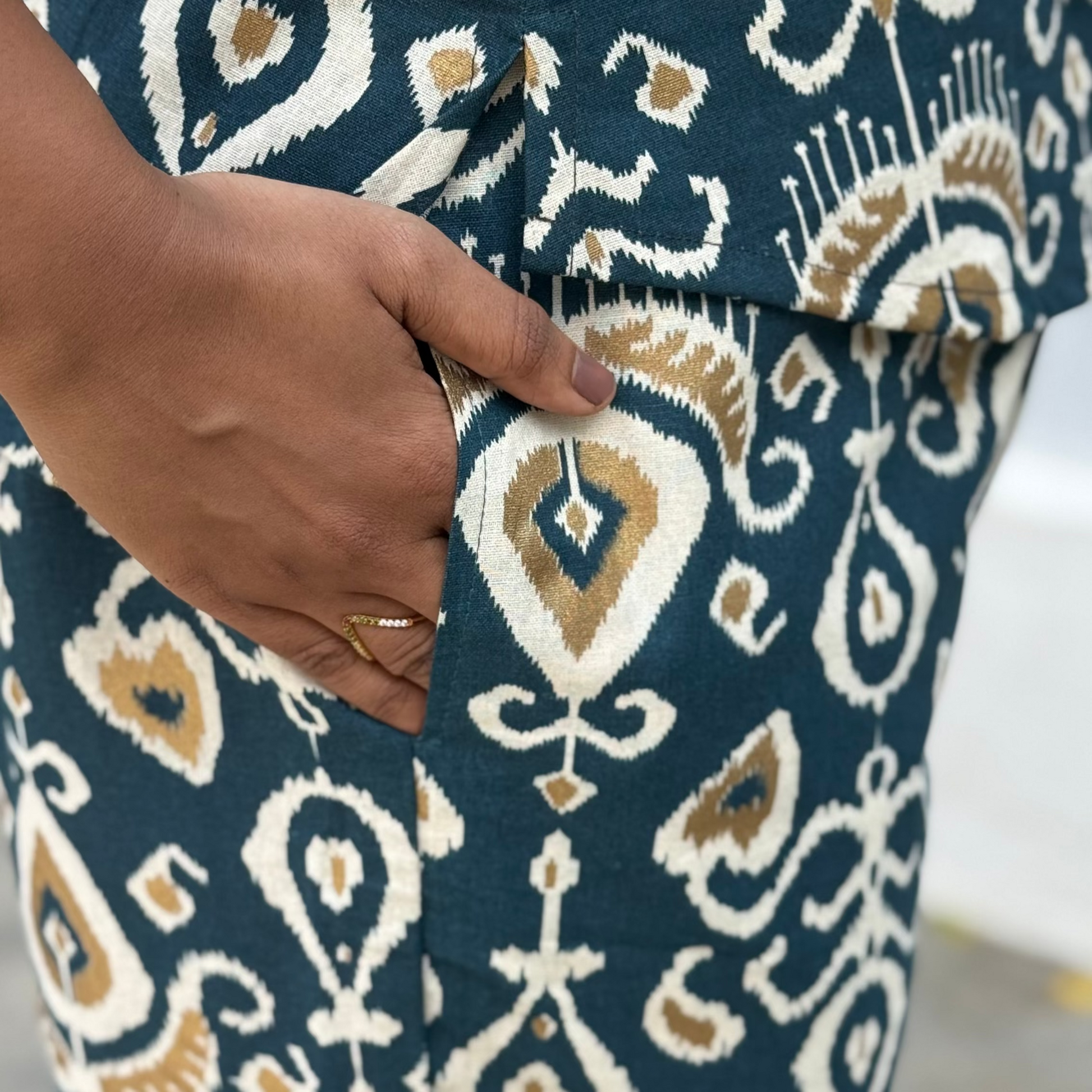 Close-up of a person wearing a patterned garment with a hand visible.